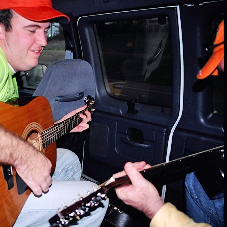 Mike and Jim playing guitars in the van.