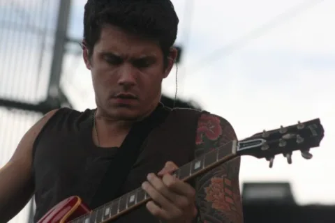 Closeup photo of John Mayer playing guitar. 