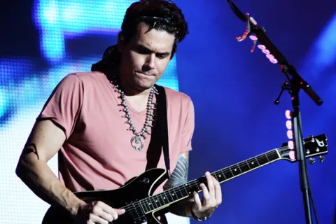 Closeup of John Mayer playing guitar on stage.