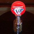 A red Nashville Predators hockey puck resting atop a miniature Stanley Cup trophy.