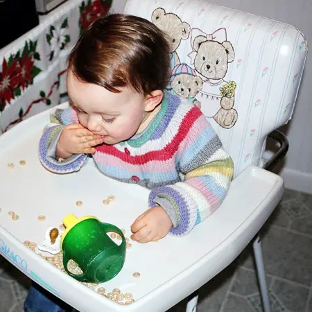 Shelby munching on Cheerios in her high chair.