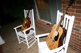 Two guitars on rocking chairs on the front porch.